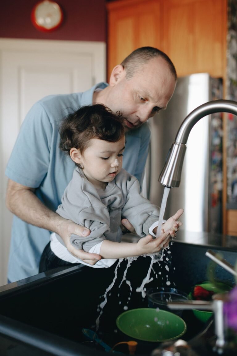 Father and child washing hands together at the sink