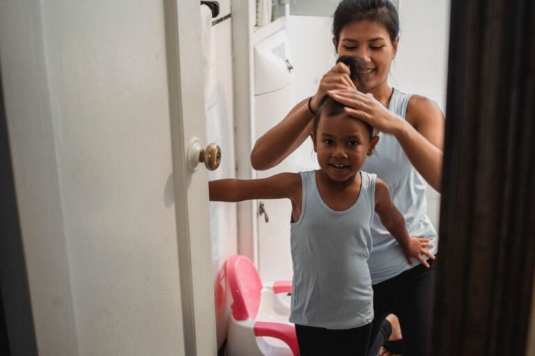 Mother smiling while doing her young daughter's hair at home