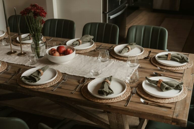 Thanksgiving dining table set with white plates, green napkins and red apples
