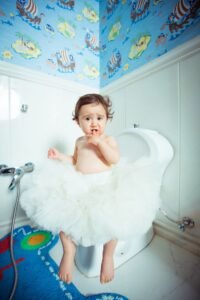 Toddler sitting on a toilet seat in a colorful bathroom